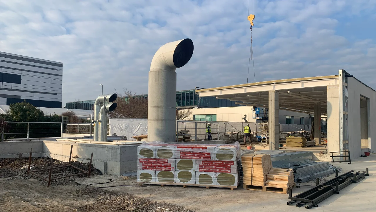 Cantiere di costruzione dell'hangar Ferrari con struttura in fase di realizzazione e canalizzazioni impiantistiche